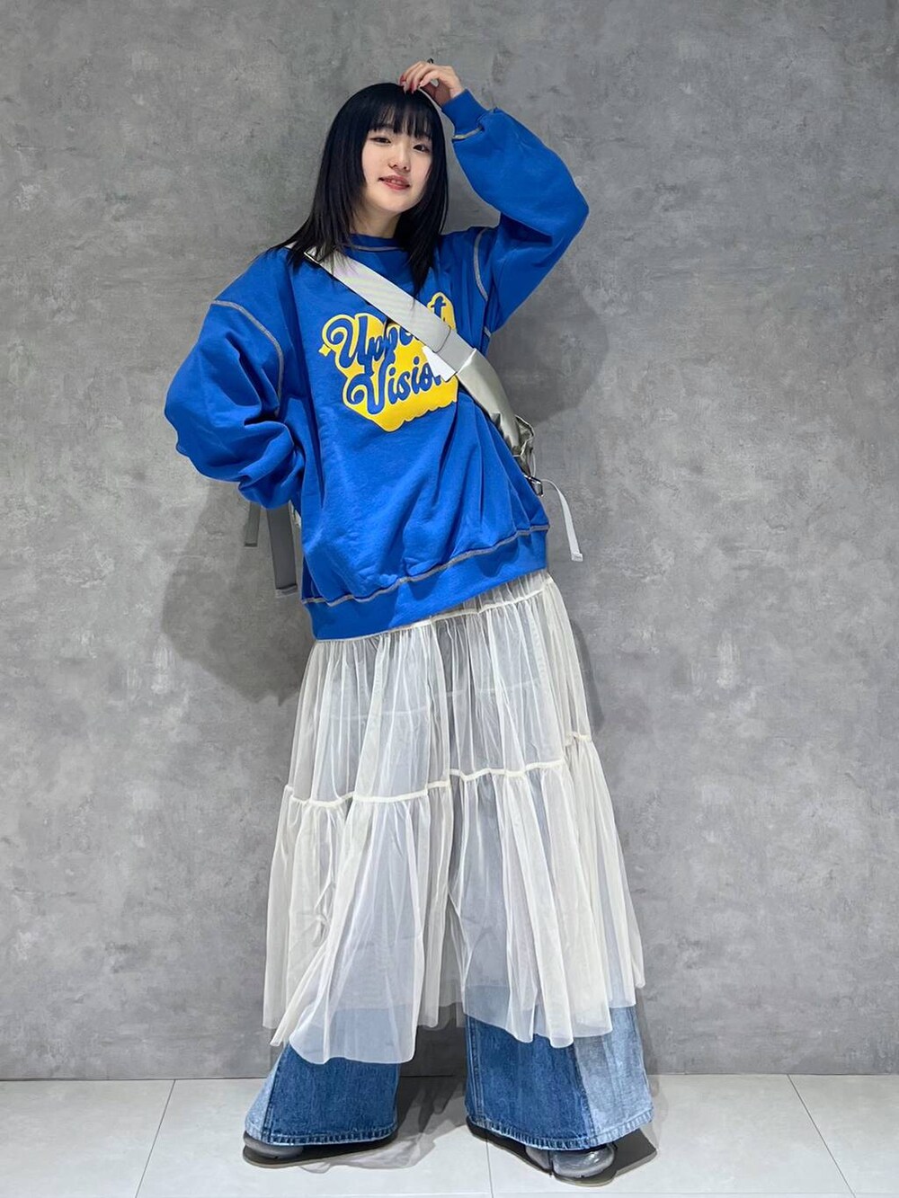 シルバー系のショルダーバッグ、ホワイト系のスカート、ブルー系のデニムパンツを着用したレディースの春コーディネートの2枚目の写真