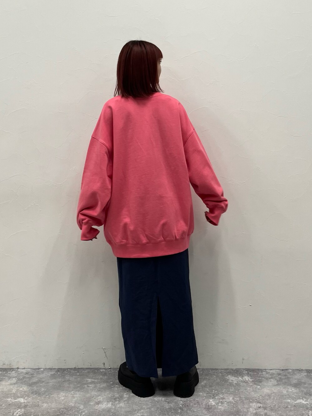 ピンク系のスウェット、ブルー系のスカート、ブラック系のブーツを着用したレディースの冬コーディネートの2枚目の写真