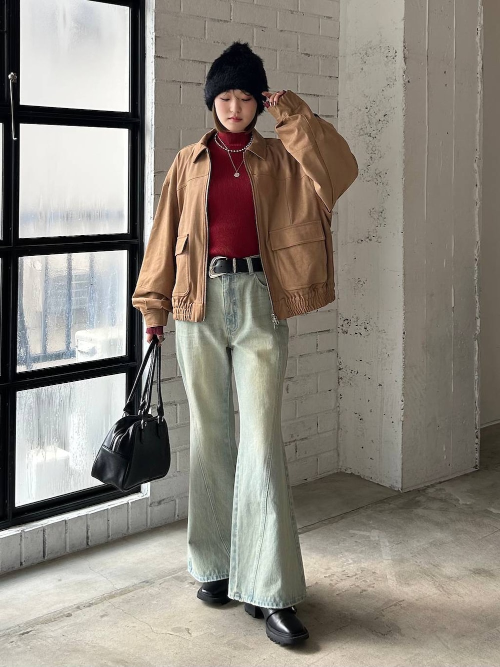 ブルー系のデニムパンツ、ブラック系のボストンバッグ、イエロー系のブルゾンを着用したレディースの秋コーディネートの2枚目の写真