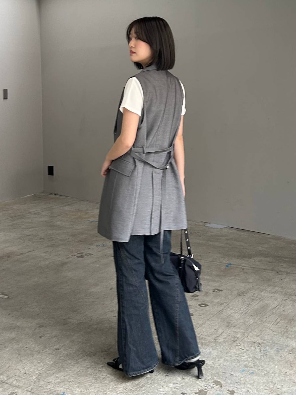 ブルー系のデニムパンツ、ブラック系のサンダル、グレー系のテーラードジャケットを着用したレディースの春コーディネートの6枚目の写真