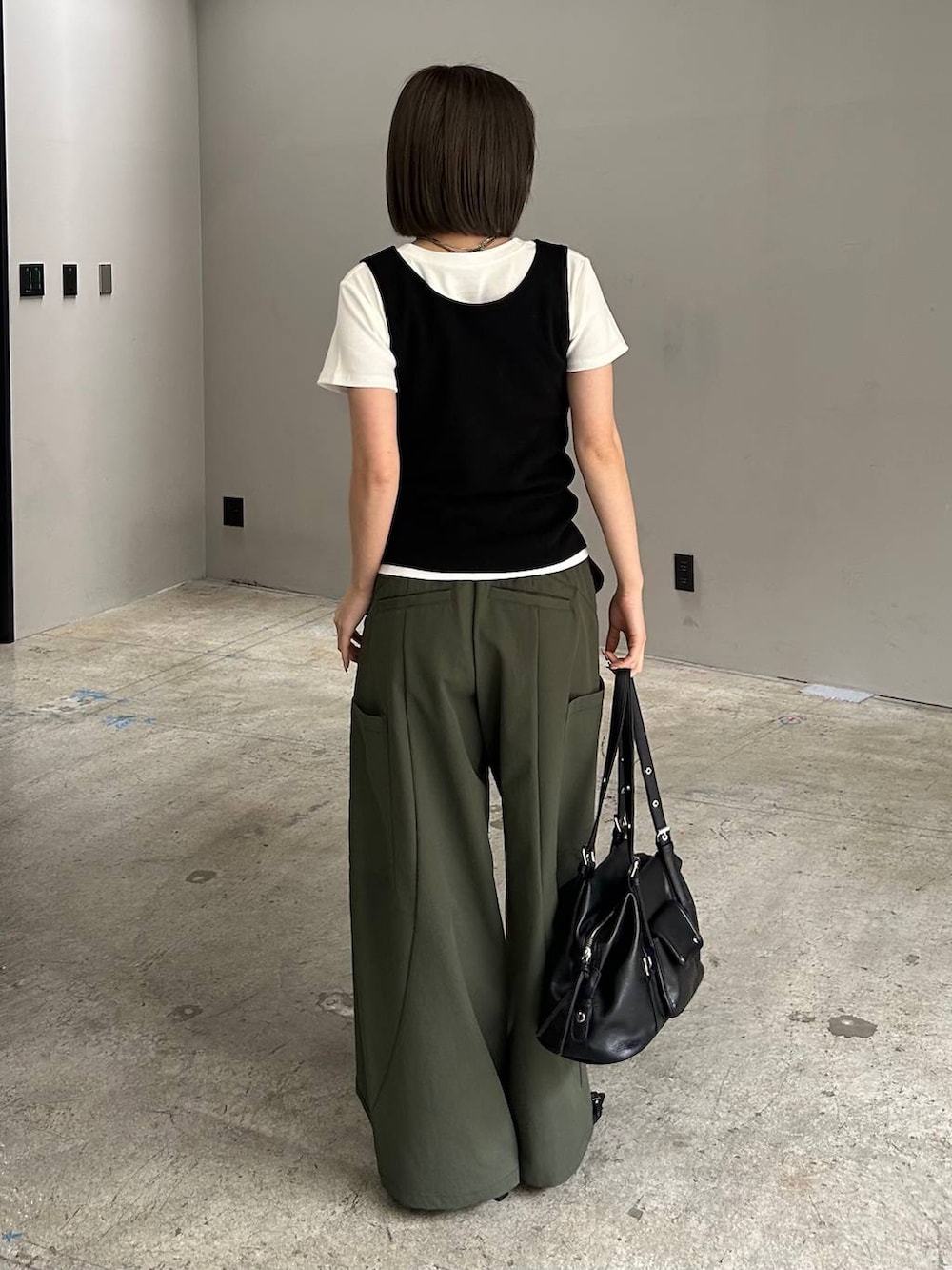 グリーン系のカーゴパンツ、ブラック系のサンダル、ブラック系のボストンバッグを着用したレディースの春コーディネートの2枚目の写真