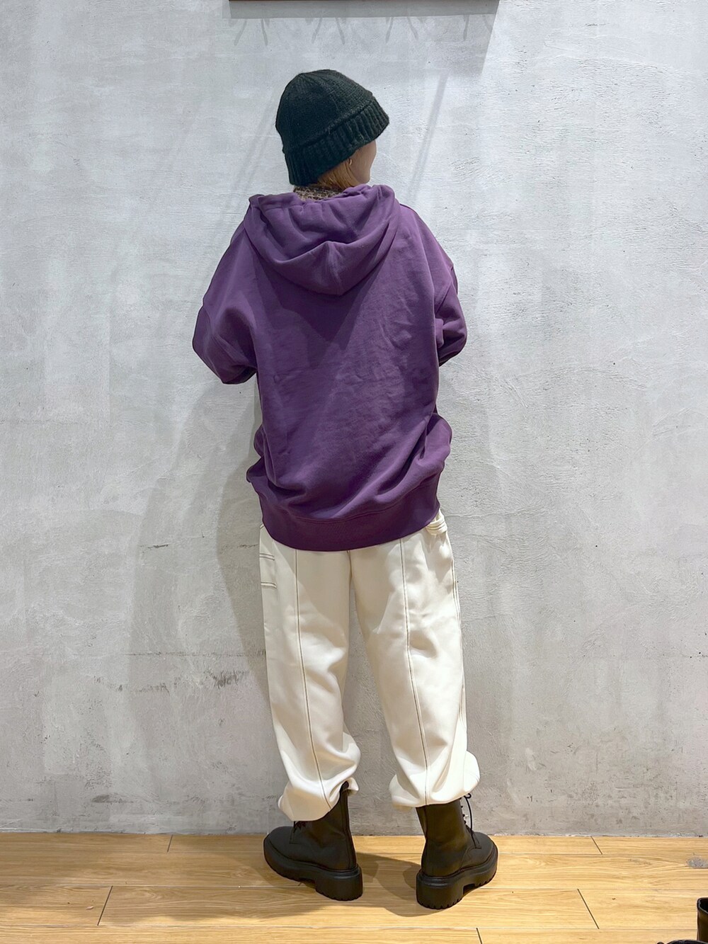 パープル系のパーカー、ホワイト系のその他パンツ、ブラック系のブーツを着用したレディースの秋コーディネートの3枚目の写真