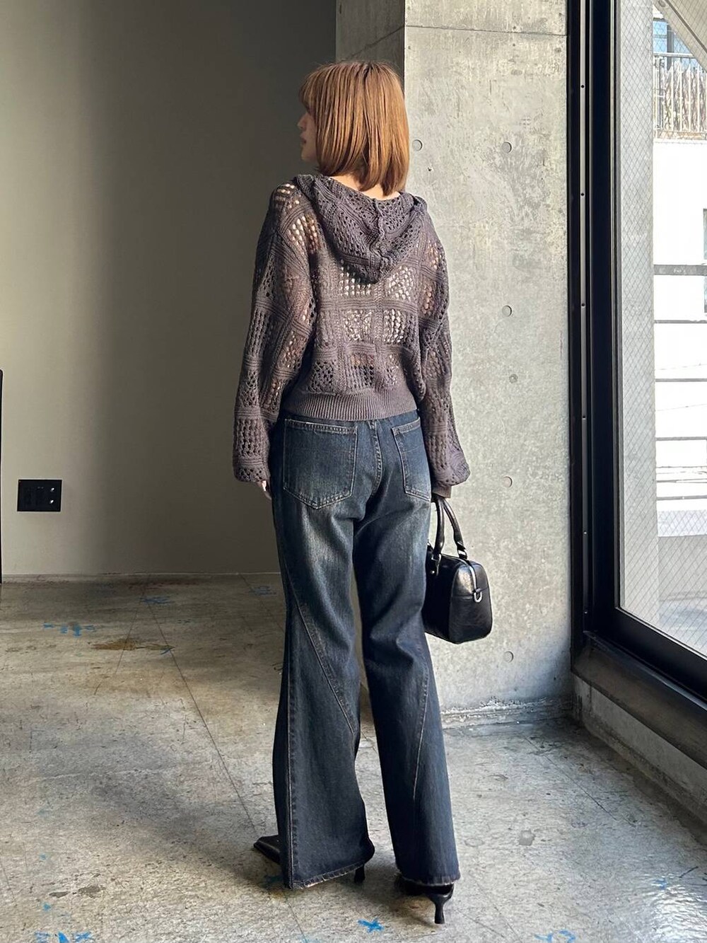 ブルー系のデニムパンツ、ブラック系のボストンバッグ、ブラック系のサンダルを着用したレディースの冬コーディネートの3枚目の写真