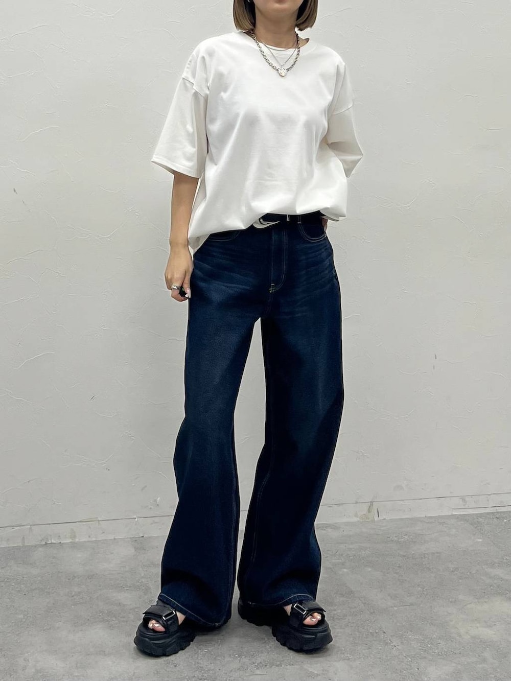 ブルー系のデニムパンツ、ブラック系のサンダル、ホワイト系のTシャツ/カットソーを着用したレディースの夏コーディネートの3枚目の写真