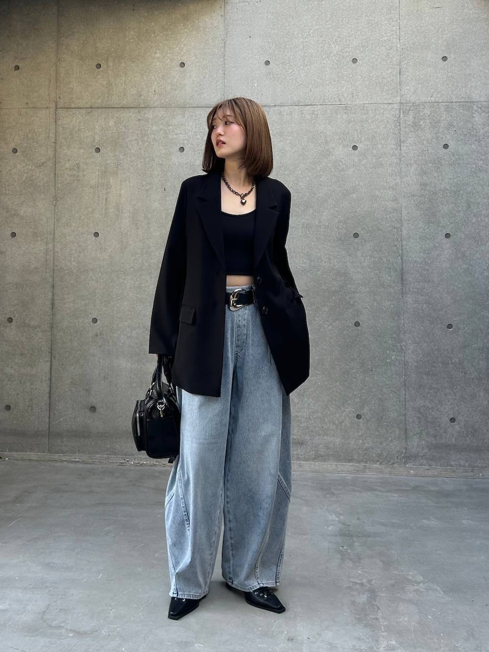 ブラック系のテーラードジャケット、ブラック系のショルダーバッグ、ブルー系のデニムパンツを着用したレディースの春コーディネートの2枚目の写真