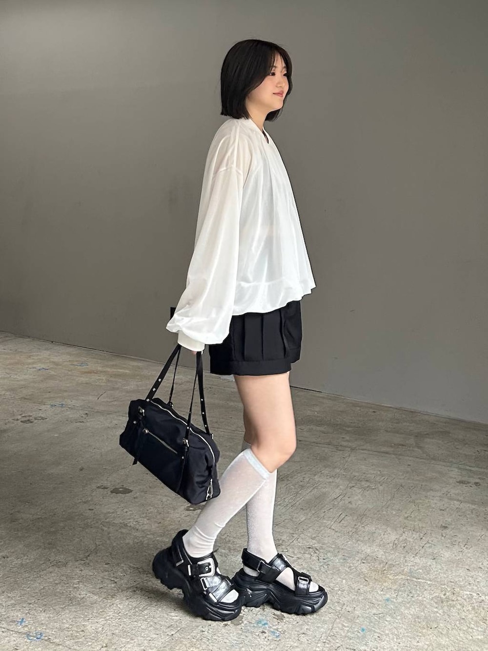 ブラック系のキャミソール、ホワイト系のブルゾン、ブラック系のサンダルを着用したレディースの春コーディネートの2枚目の写真