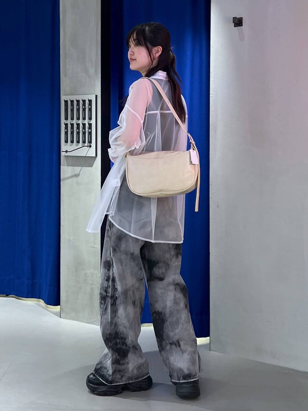 ブラック系のスニーカー、ブラック系のデニムパンツ、ベージュ系のショルダーバッグを着用したレディースの春コーディネートの3枚目の写真