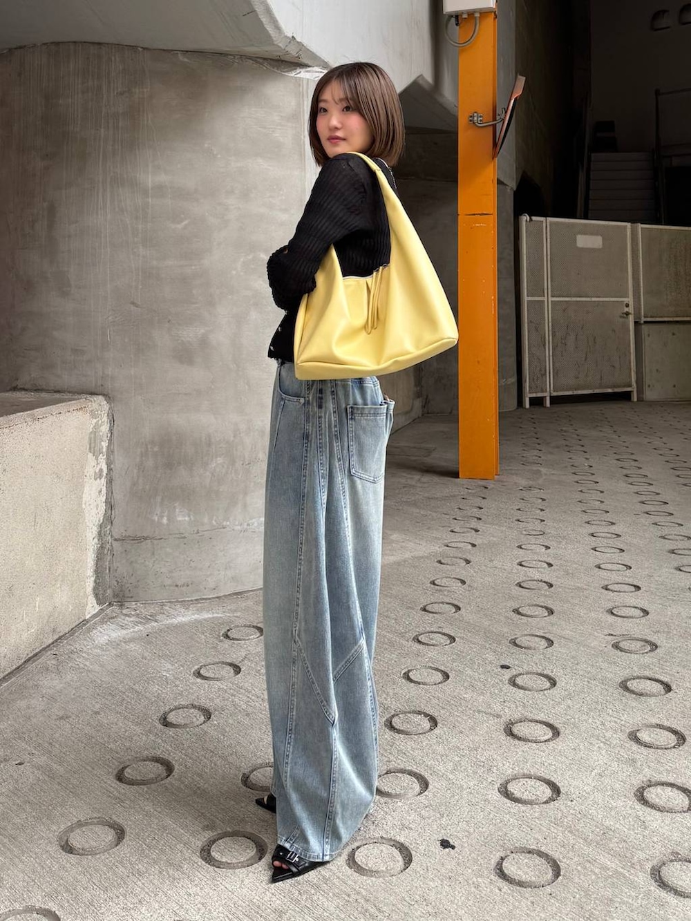 イエロー系のトートバッグ、ブルー系のデニムパンツ、ブラック系のカーディガン/ボレロを着用したレディースの春コーディネートの3枚目の写真