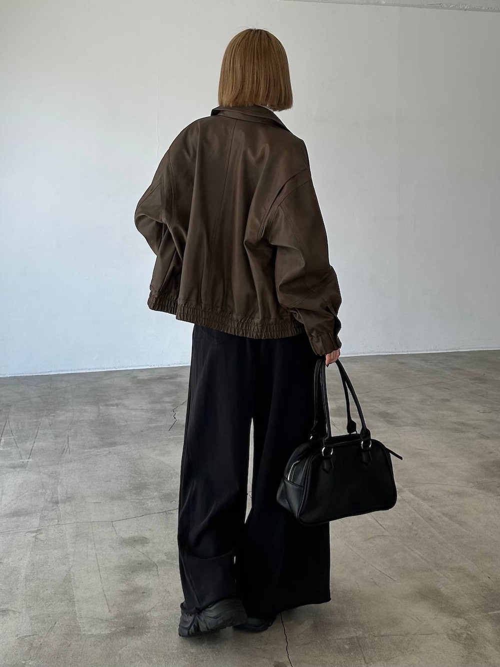 ブラック系のブーツ、ブラック系のスウェットパンツ、ブラック系のボストンバッグを着用したレディースの秋コーディネートの5枚目の写真