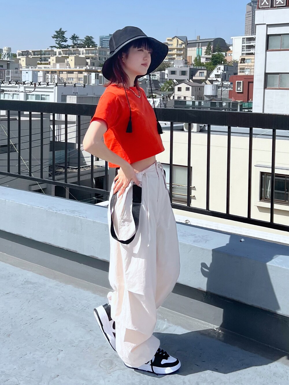 オレンジ系のTシャツ/カットソー、ホワイト系のその他パンツ、ブラック系のハットを着用したレディースの春コーディネートの2枚目の写真