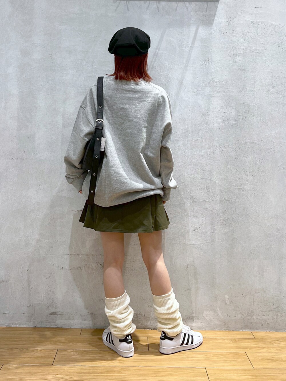 グレー系のスウェット、グリーン系のスカート、ホワイト系のスニーカーを着用したレディースの冬コーディネートの2枚目の写真