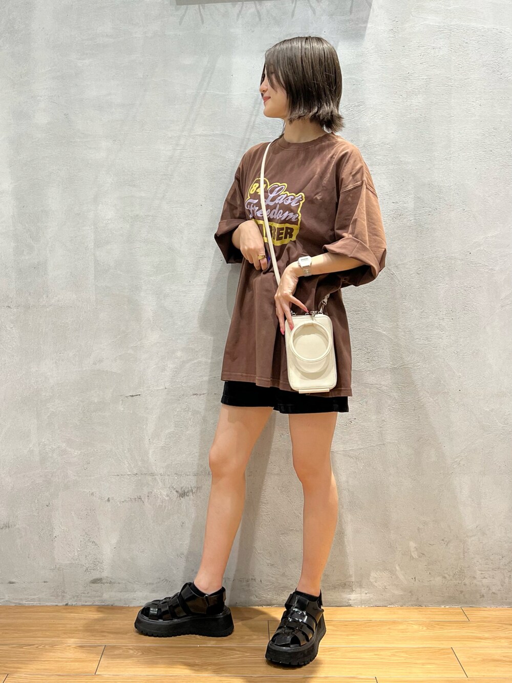 ブラウン系のTシャツ/カットソー、ブラック系のデニムパンツ、ホワイト系のショルダーバッグを着用したレディースの夏コーディネートの2枚目の写真