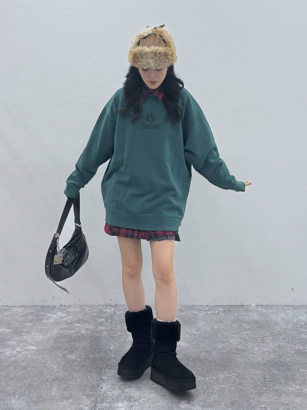 ブラック系のショルダーバッグ、ブラック系のブーツ、グリーン系のスウェットを着用したレディースの冬コーディネートの3枚目の写真