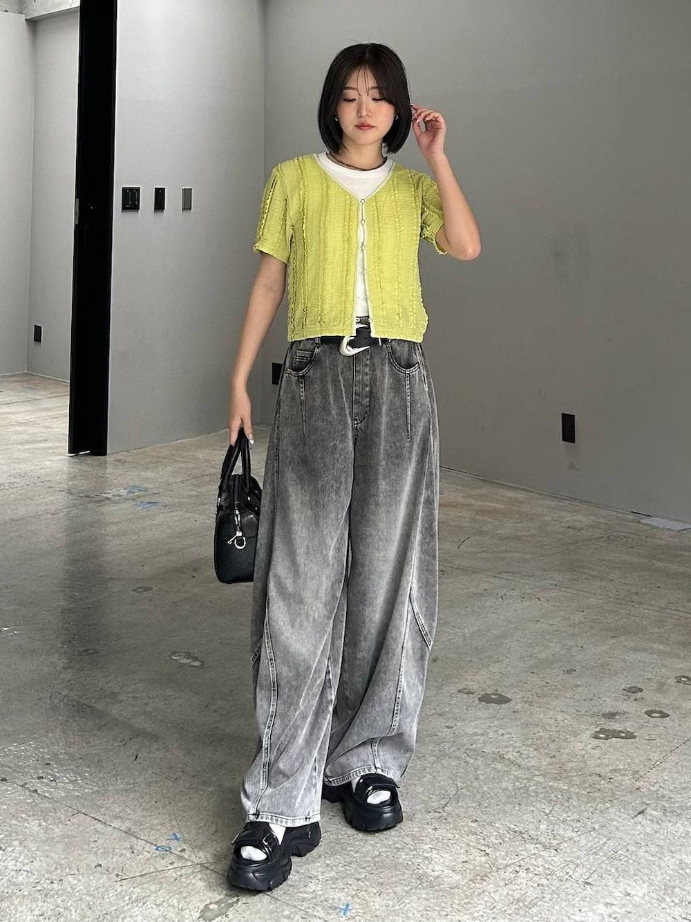 ホワイト系のボストンバッグ、ブラック系のデニムパンツ、ブラック系のサンダルを着用したレディースの春コーディネートの5枚目の写真