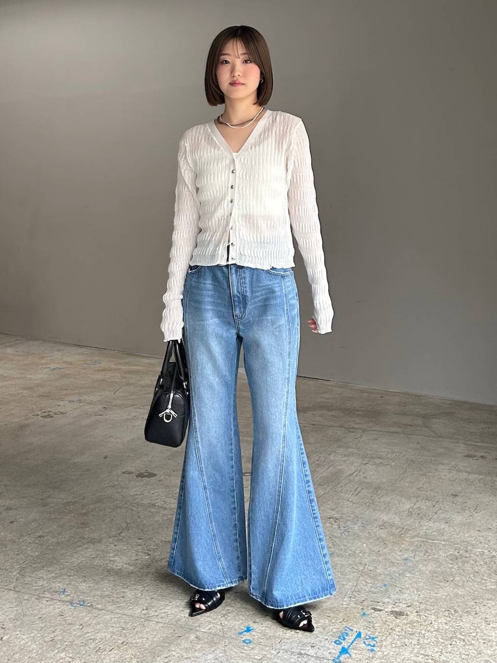 ホワイト系のキャミソール、ブルー系のデニムパンツ、ブラック系のボストンバッグを着用したレディースの春コーディネートの2枚目の写真