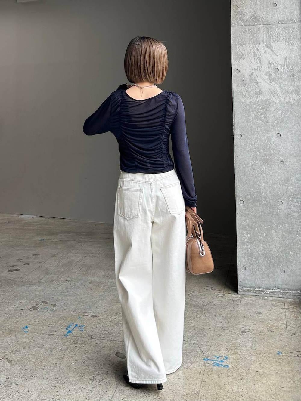 ホワイト系のスラックス、ブラウン系のボストンバッグ、ブラック系のベルトを着用したレディースの春コーディネートの4枚目の写真