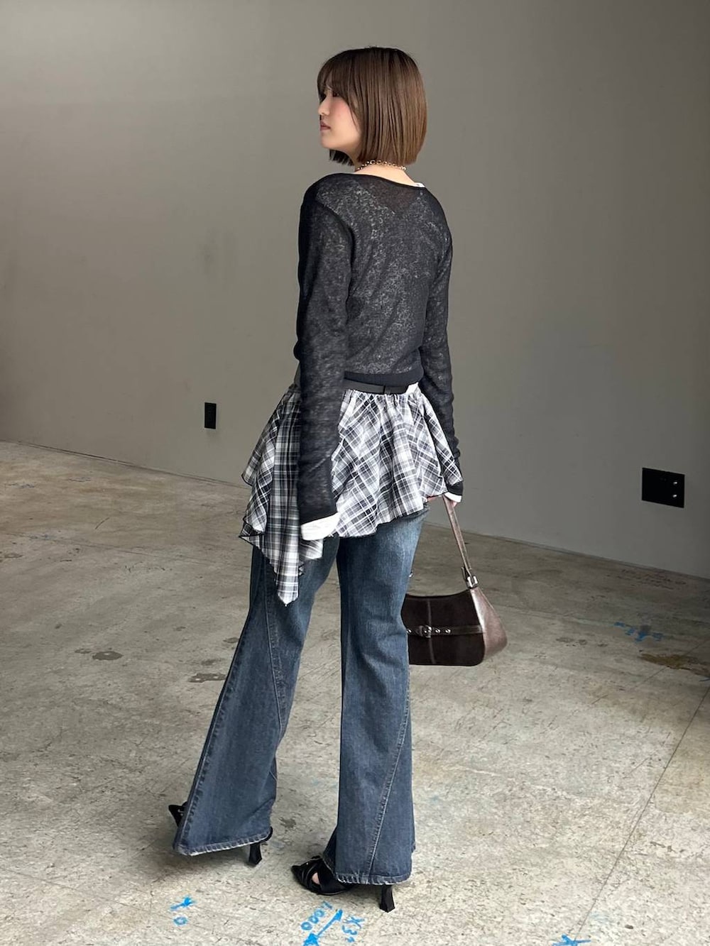 ブルー系のデニムパンツ、ブラウン系のハンドバッグ、ブラック系のTシャツ/カットソーを着用したレディースの春コーディネートの5枚目の写真