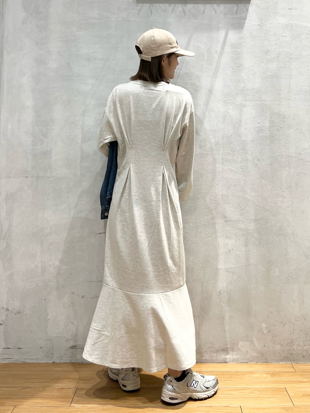 ベージュ系のワンピース、グレー系のスニーカー、ブルー系のデニムジャケットを着用したレディースの秋コーディネートの2枚目の写真