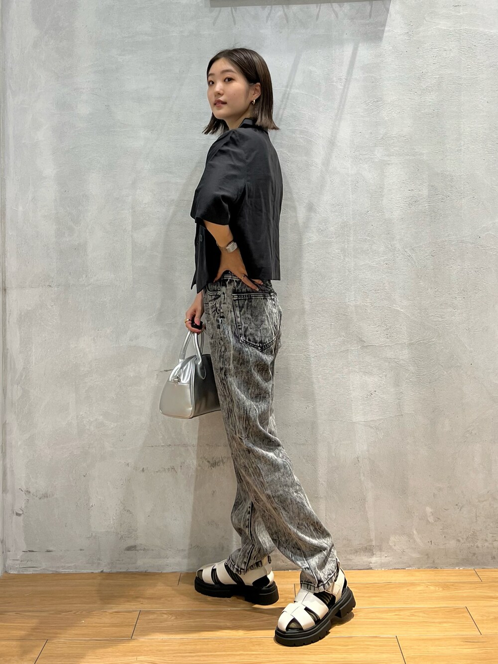 ブラック系のデニムパンツ、ホワイト系のサンダル、シルバー系のショルダーバッグを着用したレディースの夏コーディネートの2枚目の写真