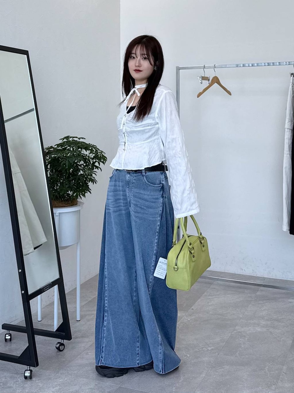 ブラック系のスニーカー、ブルー系のデニムパンツ、ホワイト系のシャツ/ブラウスを着用したレディースの春コーディネートの2枚目の写真