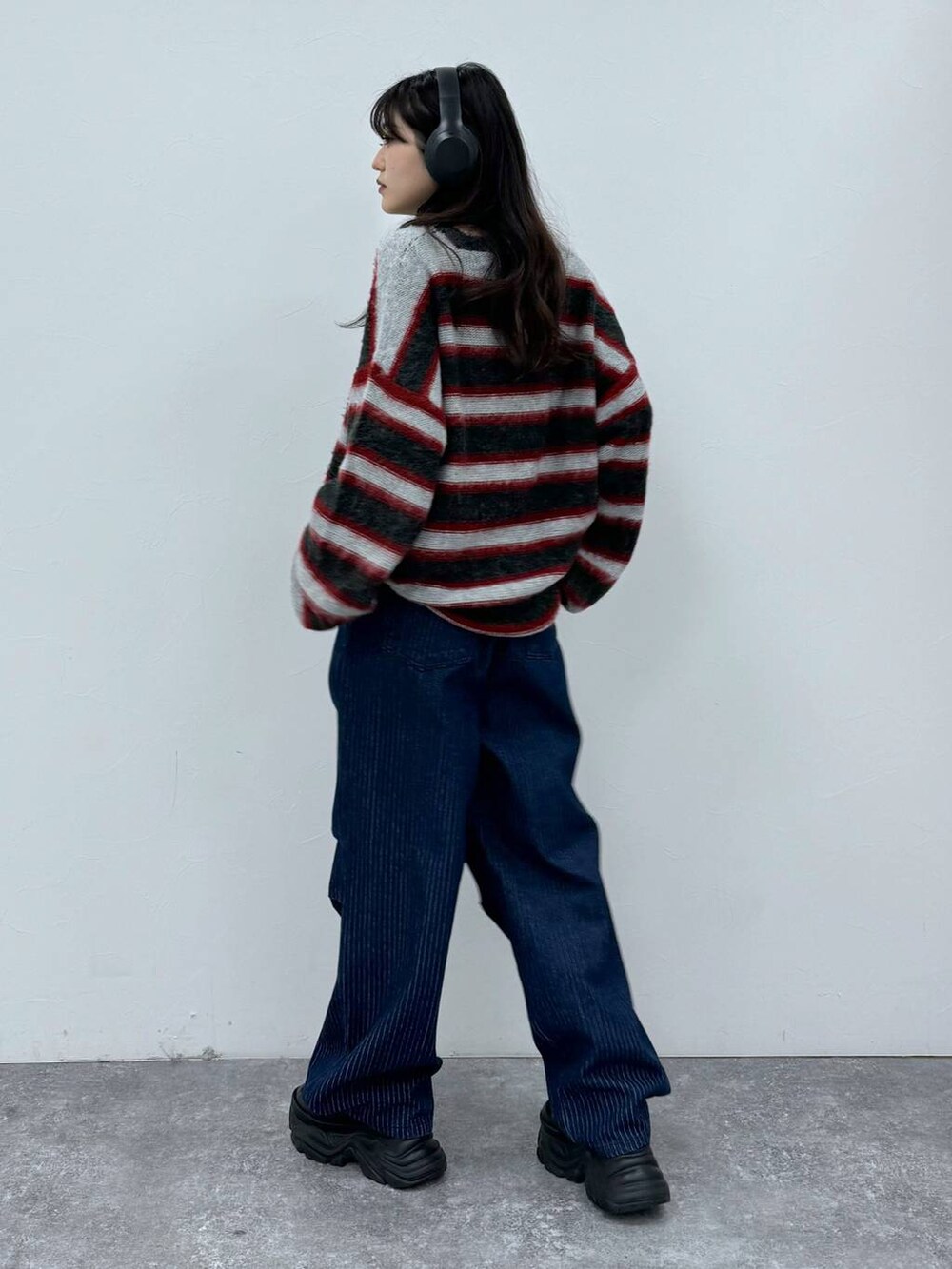 ブラック系のスニーカー、ブルー系のデニムパンツ、レッド系のニット/セーターを着用したレディースの秋コーディネートの2枚目の写真