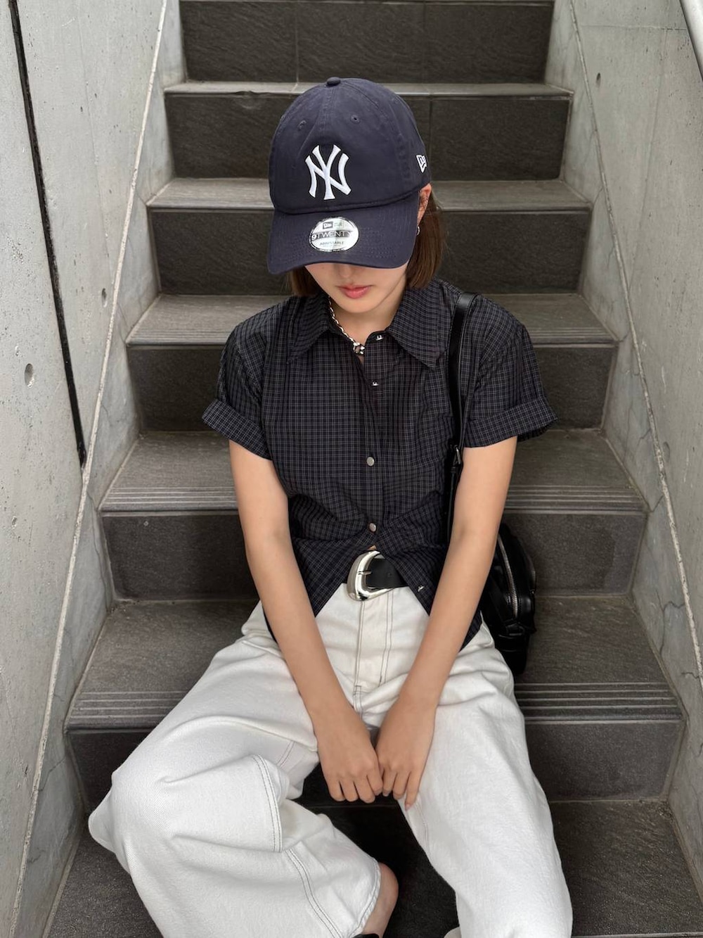 ホワイト系のデニムパンツ、ブラック系のショルダーバッグ、ブラック系のサンダルを着用したレディースの春コーディネートの6枚目の写真