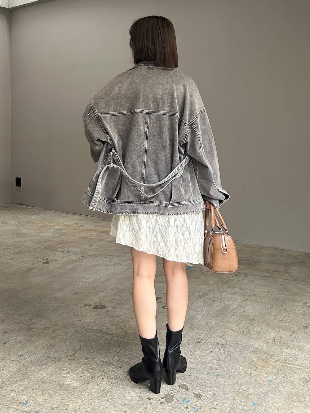 ブラウン系のボストンバッグ、ブラック系のブルゾン、ホワイト系のチュニックを着用したレディースの春コーディネートの3枚目の写真