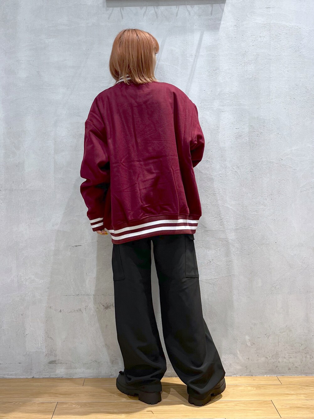 ブラック系のカーゴパンツ、ブラック系のブーツ、レッド系のブルゾンを着用したレディースの秋コーディネートの3枚目の写真