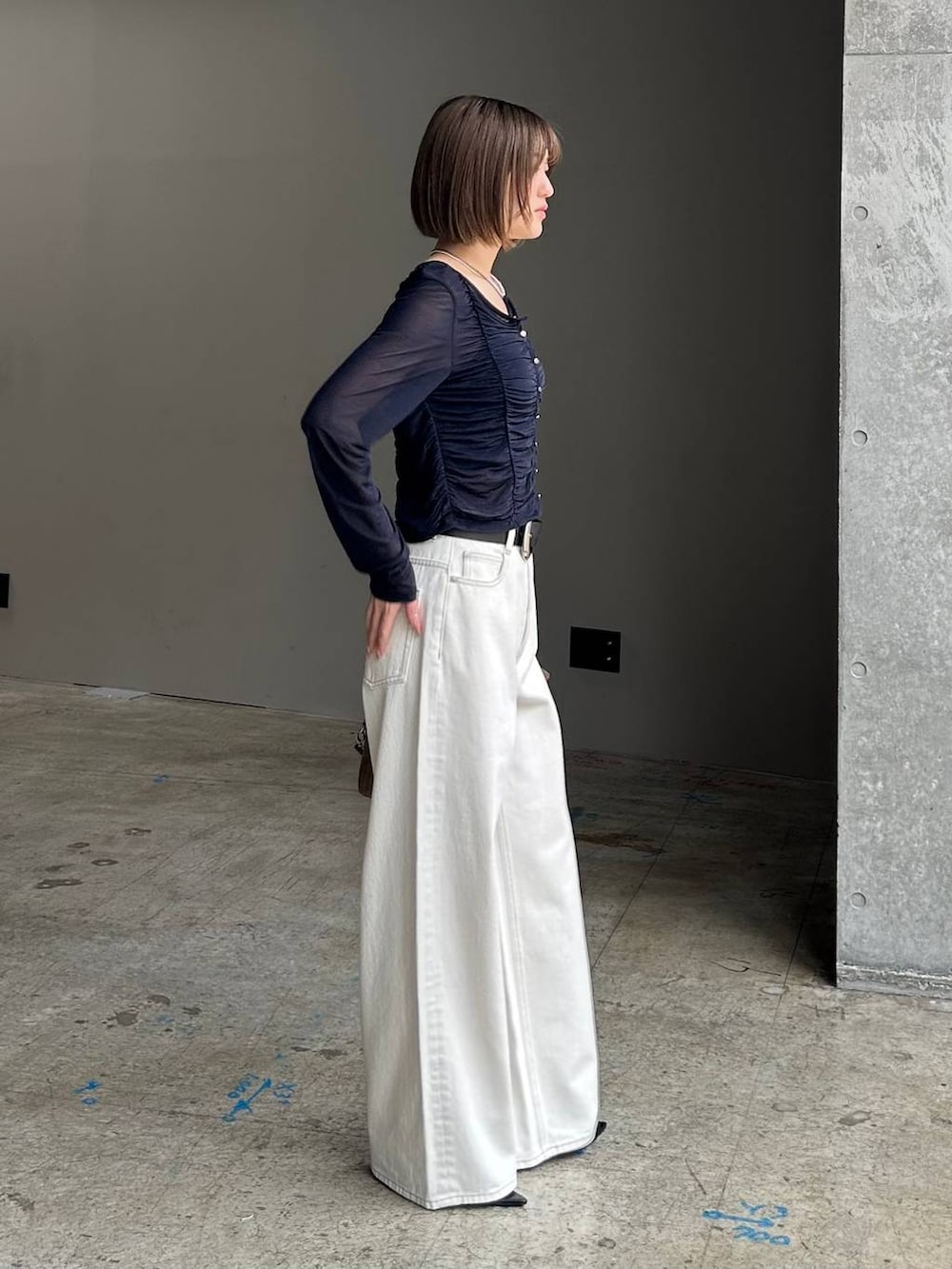 ホワイト系のスラックス、ブラウン系のボストンバッグ、ブラック系のベルトを着用したレディースの春コーディネートの2枚目の写真