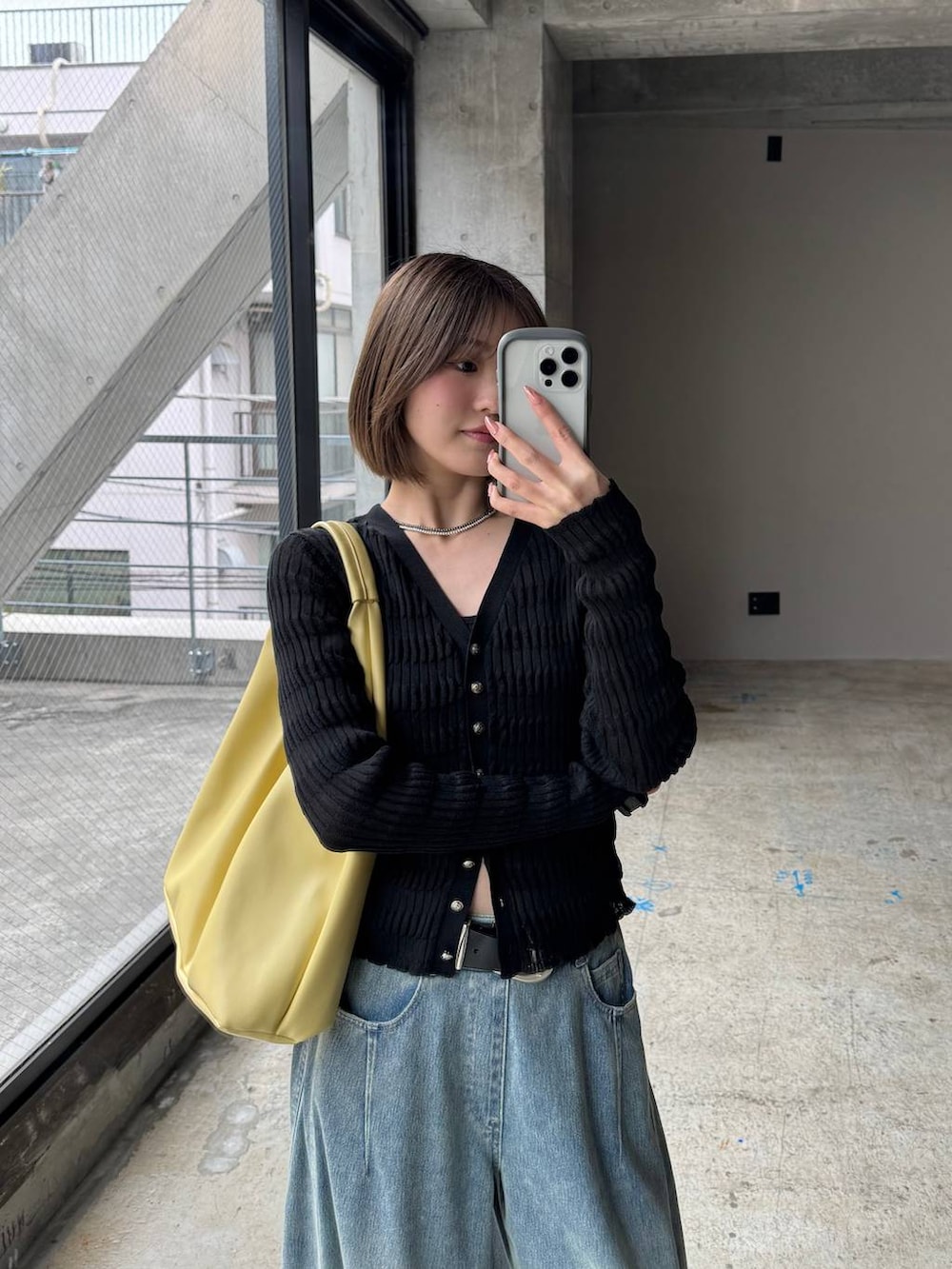 イエロー系のトートバッグ、ブルー系のデニムパンツ、ブラック系のカーディガン/ボレロを着用したレディースの春コーディネートの5枚目の写真