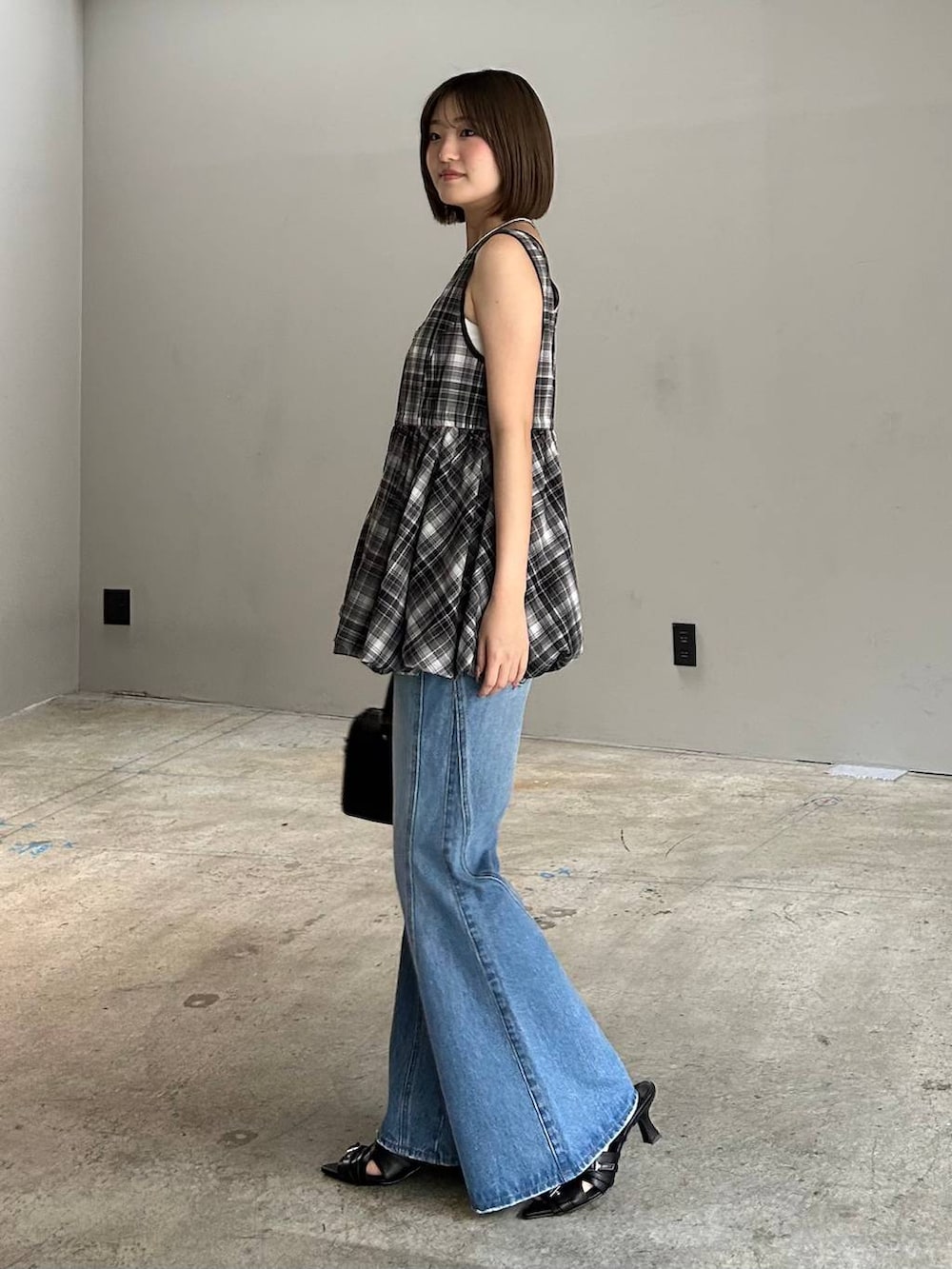 ブルー系のデニムパンツ、ブラック系のボストンバッグ、ブラック系のサンダルを着用したレディースの春コーディネートの3枚目の写真