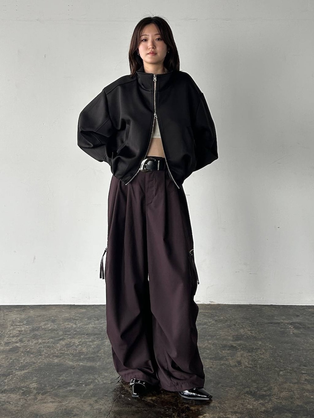 ブラウン系のカーゴパンツ、ブラック系のブルゾン、ブラック系のベルトを着用したレディースの秋コーディネートの2枚目の写真
