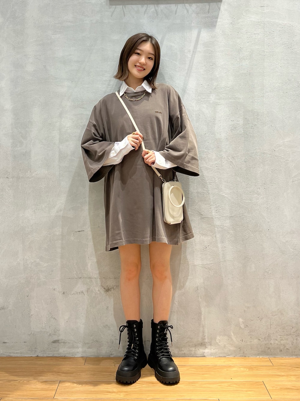 ブラウン系のTシャツ/カットソー、ブラック系のブーツ、ホワイト系のショルダーバッグを着用したレディースの秋コーディネートの5枚目の写真