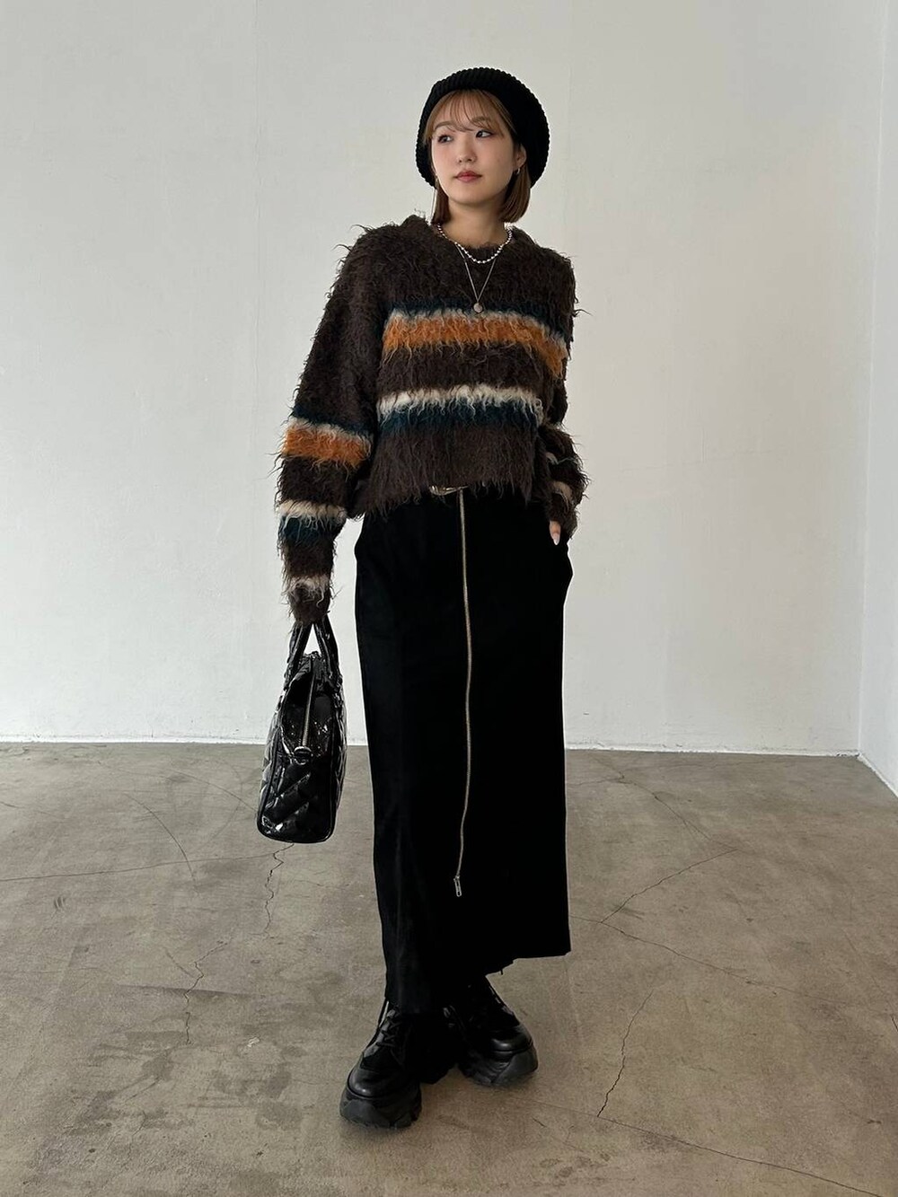 ブラック系のブーツ、ベージュ系のボストンバッグ、ブラウン系のニット/セーターを着用したレディースの冬コーディネートの5枚目の写真