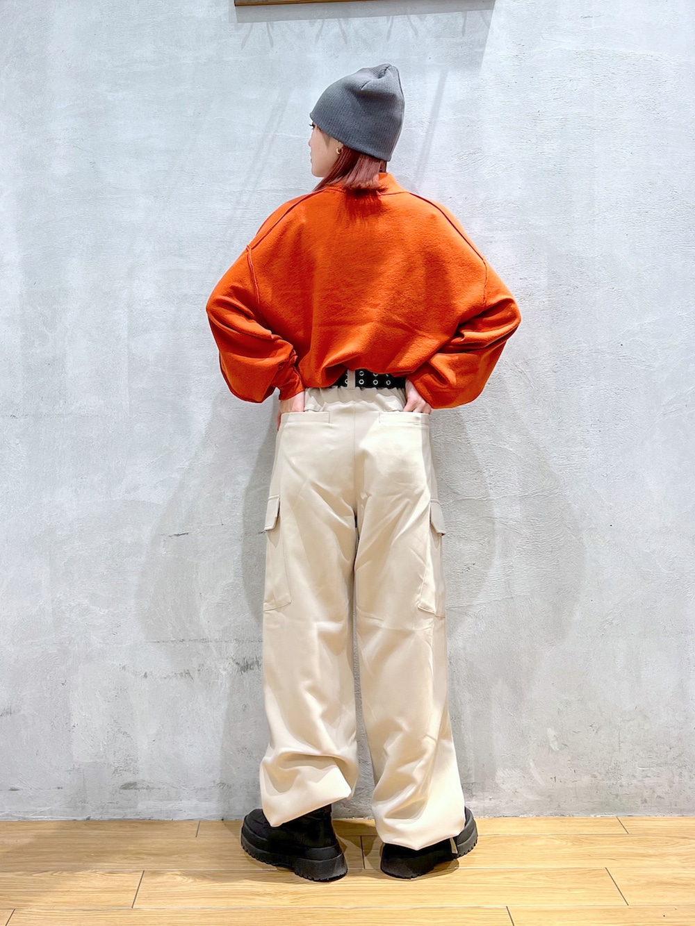 ベージュ系のカーゴパンツ、オレンジ系のTシャツ/カットソー、ブラック系のブーツを着用したレディースの冬コーディネートの2枚目の写真