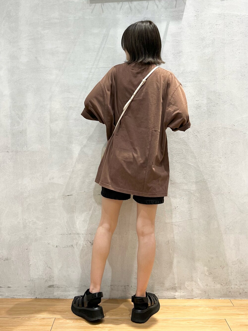 ブラウン系のTシャツ/カットソー、ブラック系のデニムパンツ、ホワイト系のショルダーバッグを着用したレディースの夏コーディネートの3枚目の写真