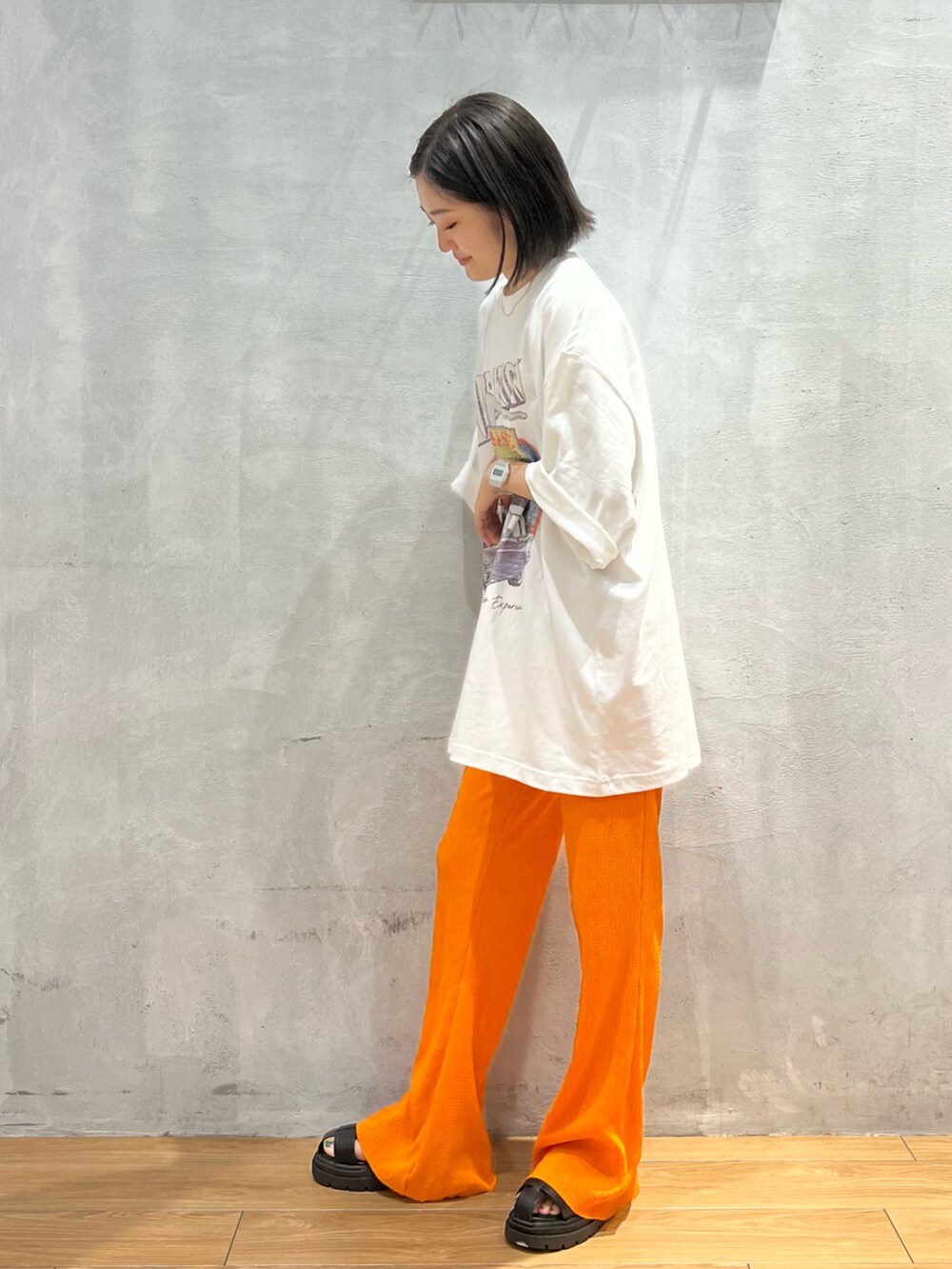 オレンジ系のその他パンツ、ホワイト系のTシャツ/カットソー、ブラック系のサンダルを着用したレディースの夏コーディネートの2枚目の写真