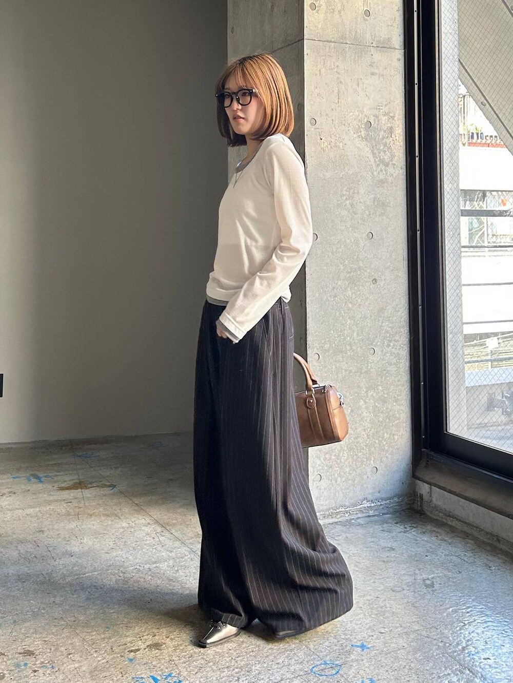 ブラウン系のボストンバッグ、ブラック系のサンダル、ブラック系のスラックスを着用したレディースの冬コーディネートの4枚目の写真