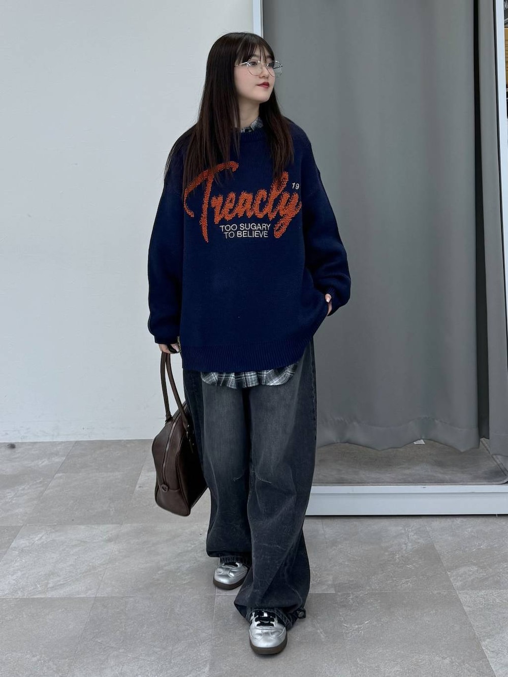 ブルー系のニット/セーター、ブラウン系のボストンバッグ、ブラック系のデニムパンツを着用したレディースの冬コーディネートの2枚目の写真