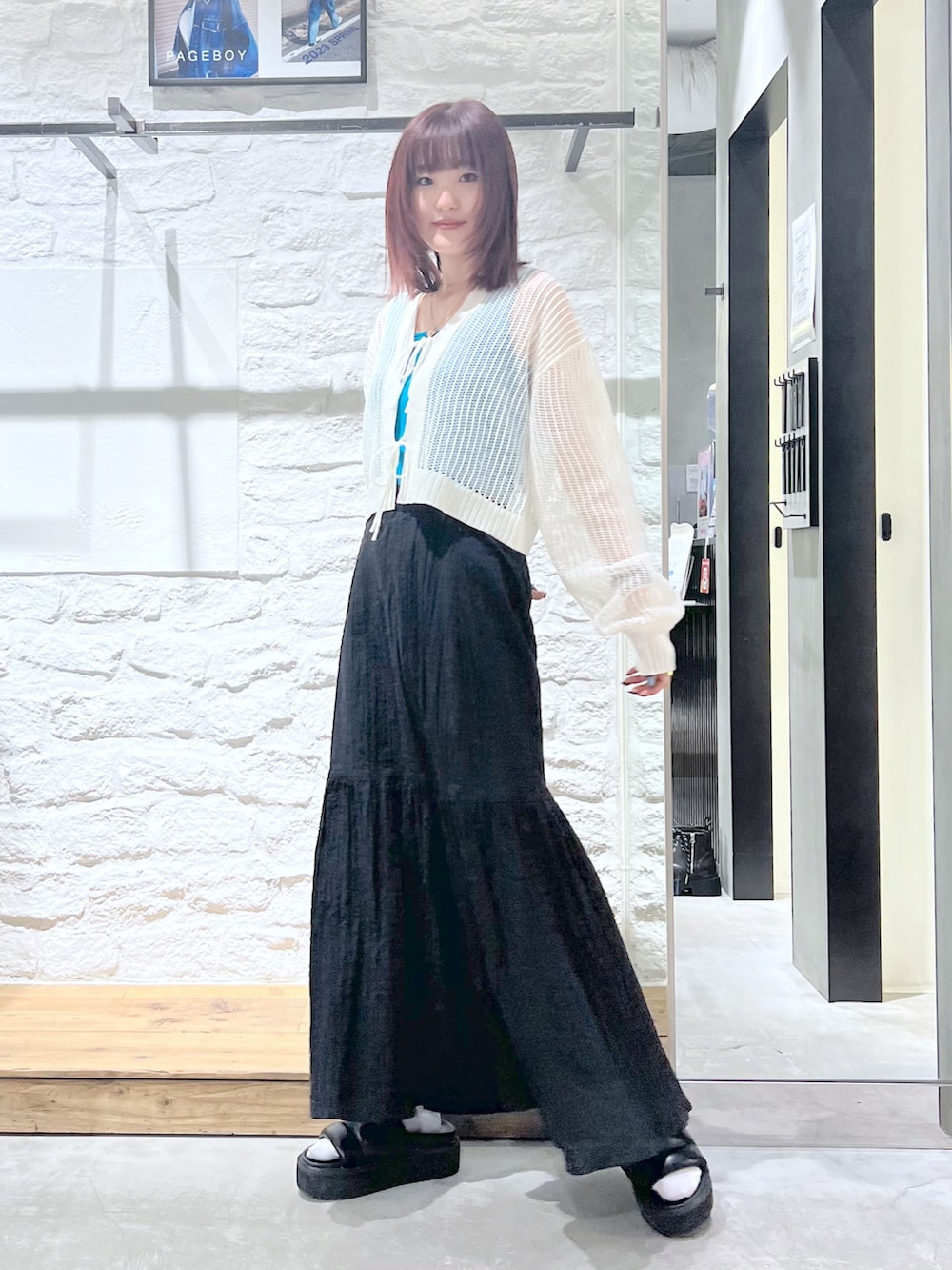 ホワイト系のカーディガン/ボレロ、ブラック系のスカート、ブラック系のサンダルを着用したレディースの春コーディネートの2枚目の写真