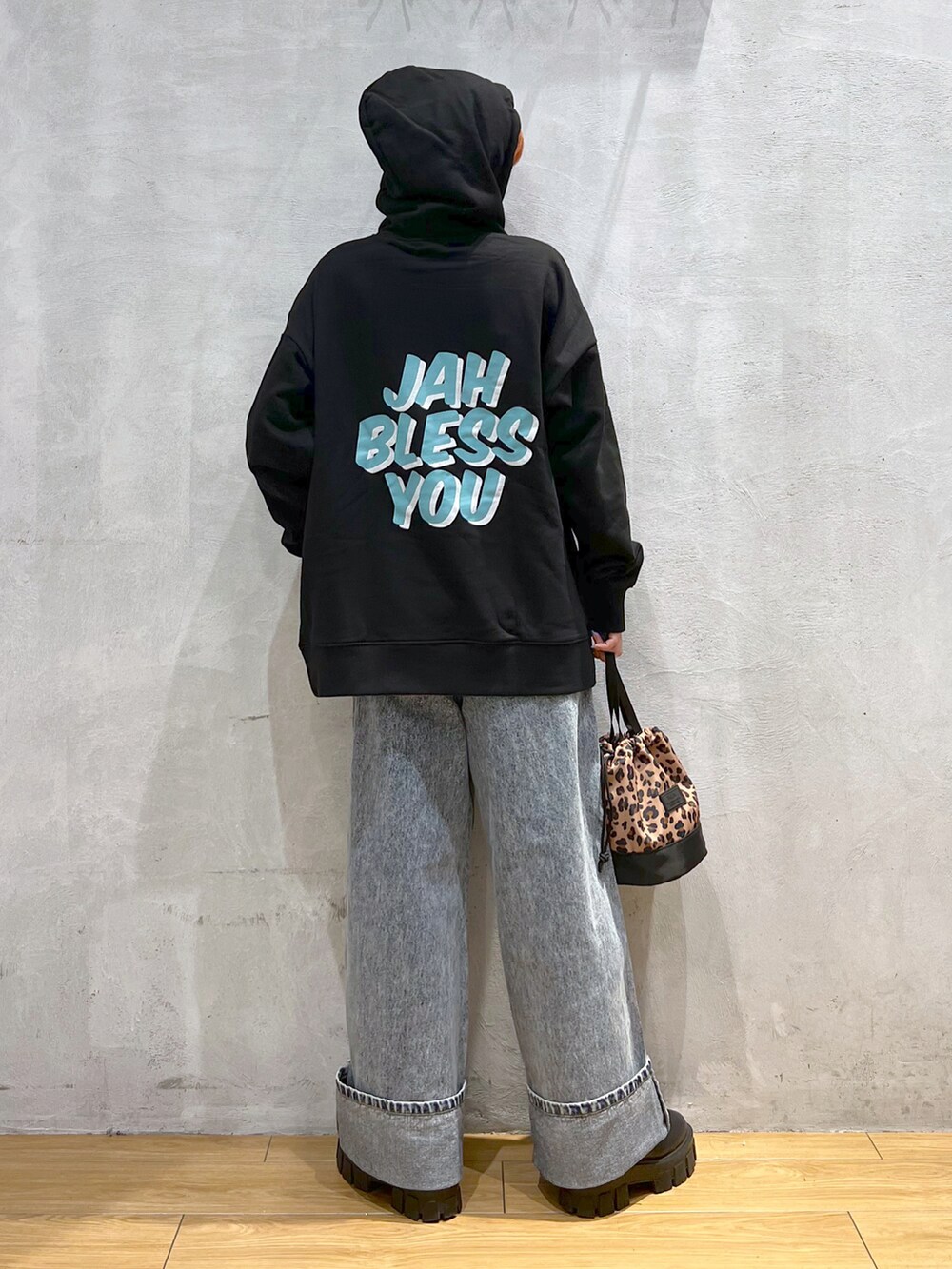 ブルー系のデニムパンツ、ブラック系のブーツ、ブラック系のパーカーを着用したレディースの秋コーディネートの3枚目の写真