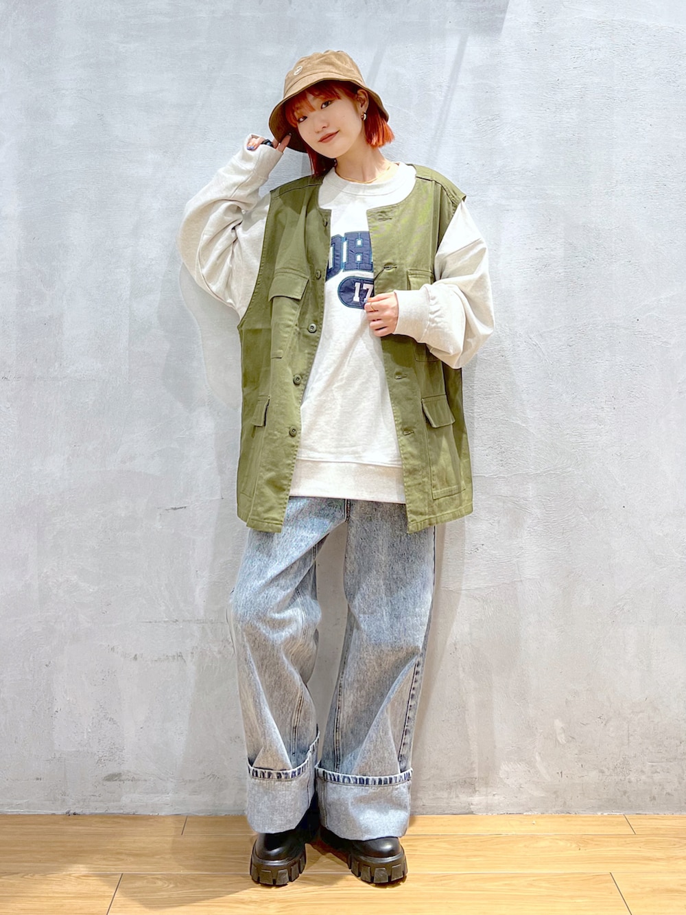 ブルー系のデニムパンツ、グリーン系のベスト、ベージュ系のスウェットを着用したレディースの秋コーディネートの2枚目の写真