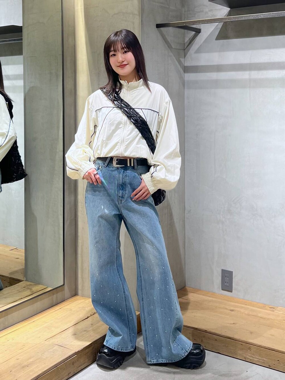 ホワイト系のブルゾン、ブルー系のキャミソール、ブルー系のデニムパンツを着用したレディースの冬コーディネートの5枚目の写真