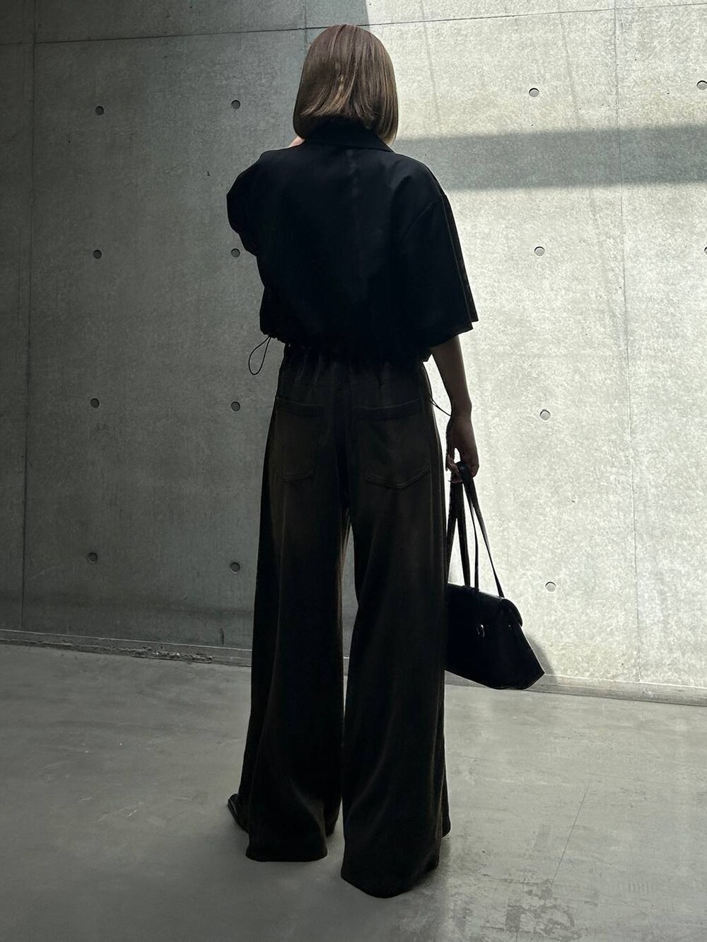 ブラック系のデニムパンツ、ブラック系のキャミソール、ブラック系のショルダーバッグを着用したレディースの夏コーディネートの6枚目の写真