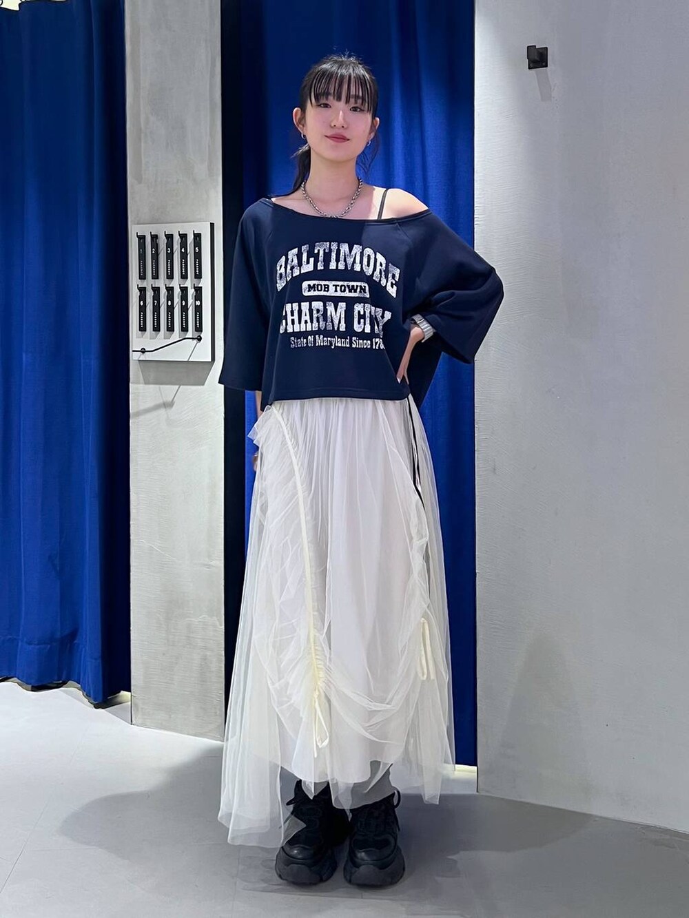 ブラック系のスニーカー、ホワイト系のスカート、ブルー系のTシャツ/カットソーを着用したレディースの夏コーディネートの6枚目の写真