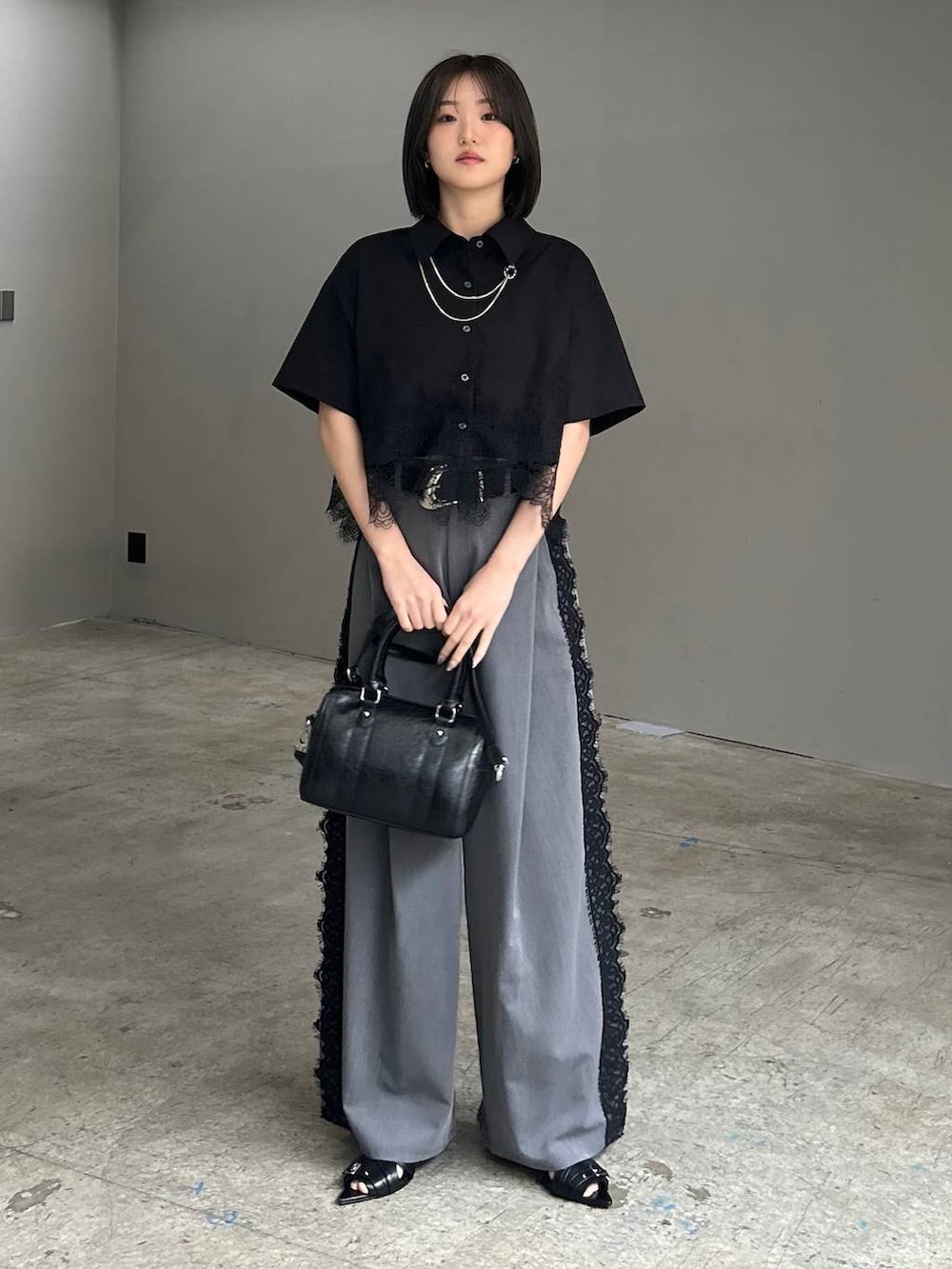 ブラック系のサンダル、グレー系のスラックス、ブラック系のシャツ/ブラウスを着用したレディースの春コーディネートの2枚目の写真
