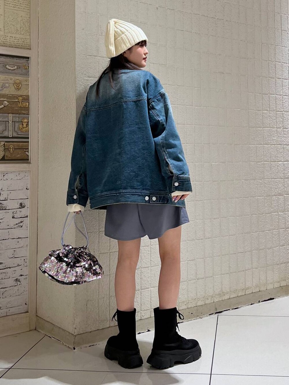 ホワイト系のニット/セーター、ブルー系のデニムジャケット、ブラック系のブーツを着用したレディースの冬コーディネートの5枚目の写真