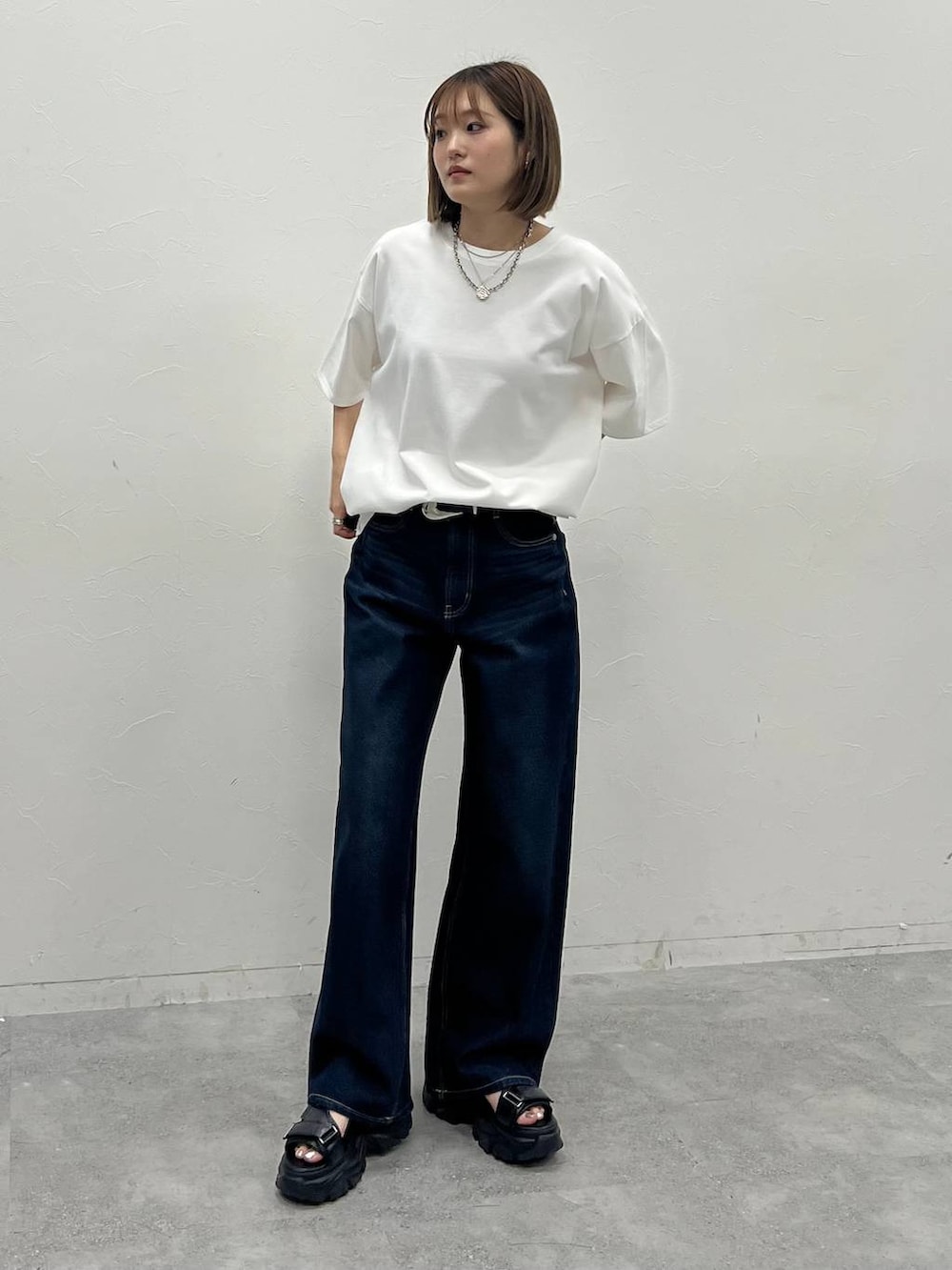 ブルー系のデニムパンツ、ブラック系のサンダル、ホワイト系のTシャツ/カットソーを着用したレディースの夏コーディネートの4枚目の写真