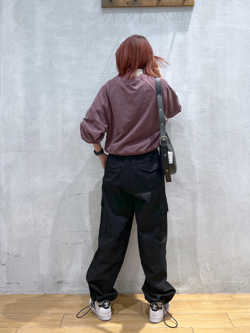 ブラック系のカーゴパンツ、レッド系のスウェット、ブラック系のショルダーバッグを着用したレディースの冬コーディネートの2枚目の写真