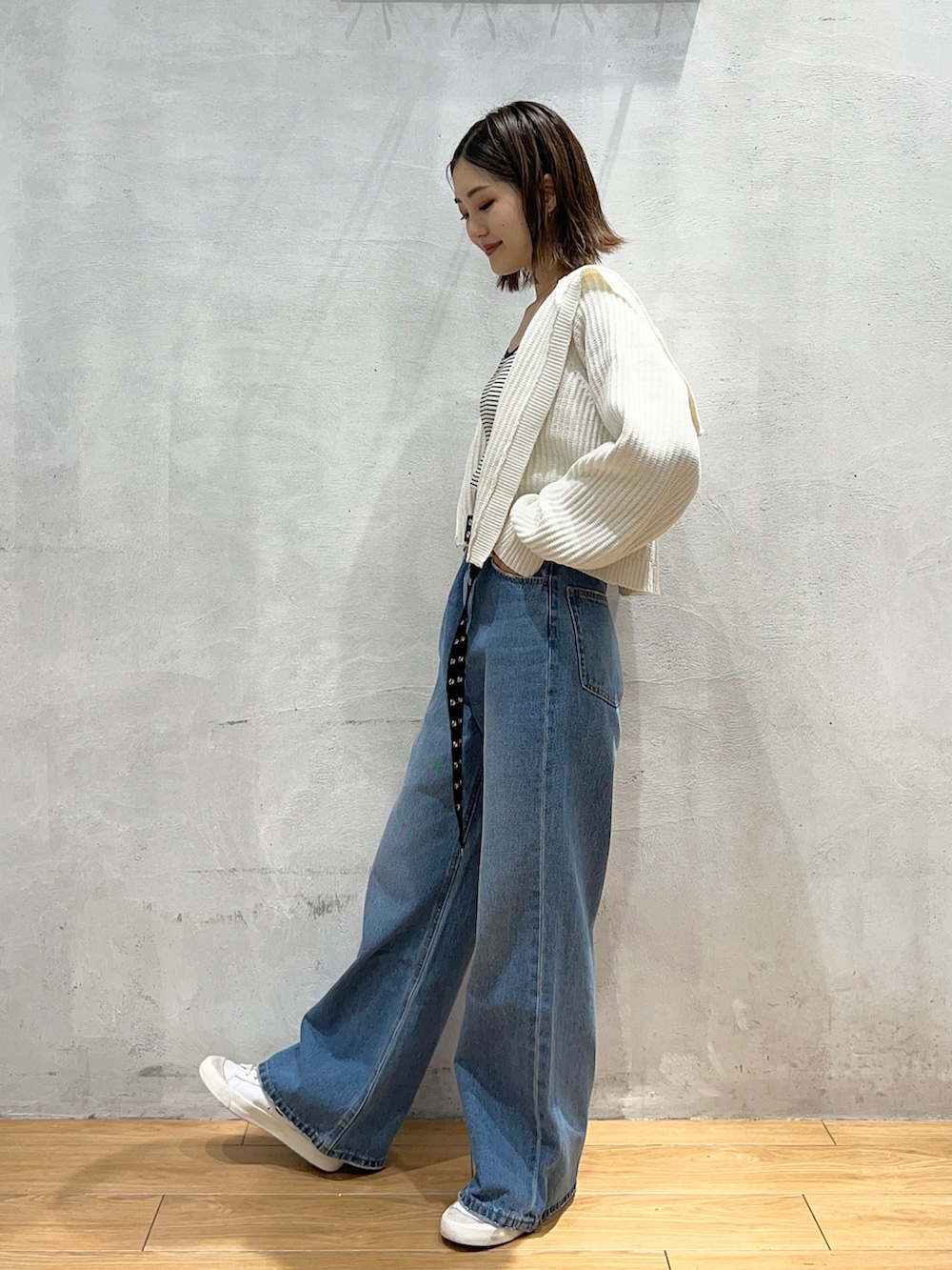 ブルー系のデニムパンツ、ホワイト系のカーディガン/ボレロ、ホワイト系のキャミソールを着用したレディースの秋コーディネートの2枚目の写真